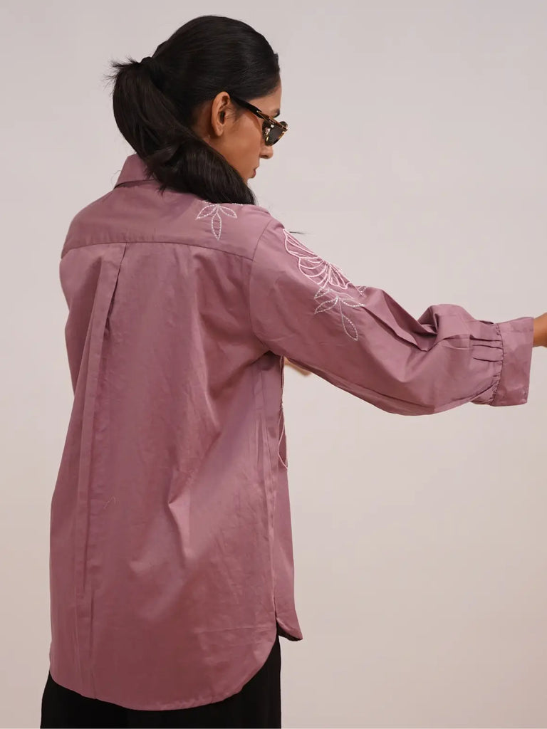 Person wearing a pink embroidered shirt 